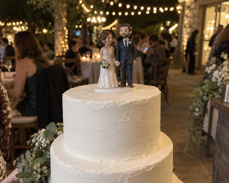 A hand-painted bride and groom figurine cake topper on a white wedding cake